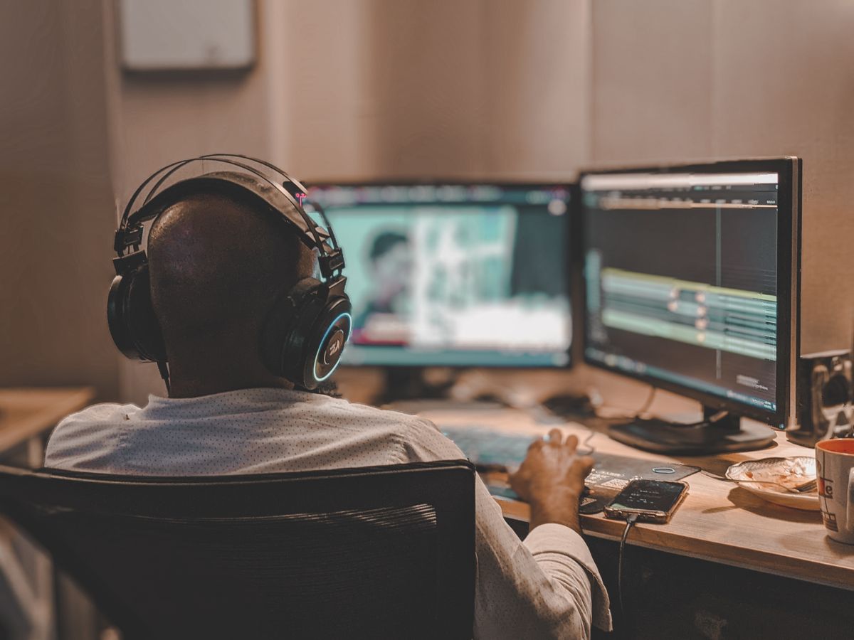 A freelance editor at a desk with headphones on, working through a timeline
