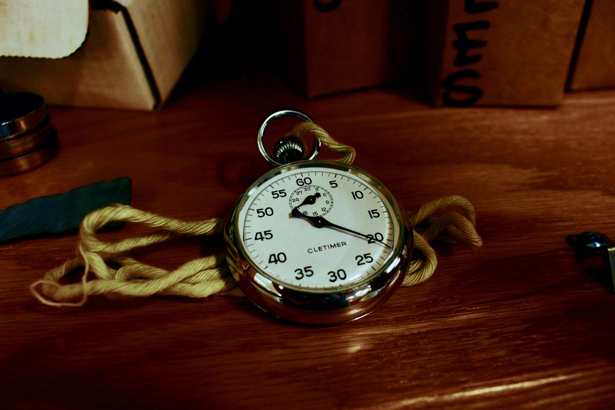 A stopwatch resting on a clean desk next to a notebook