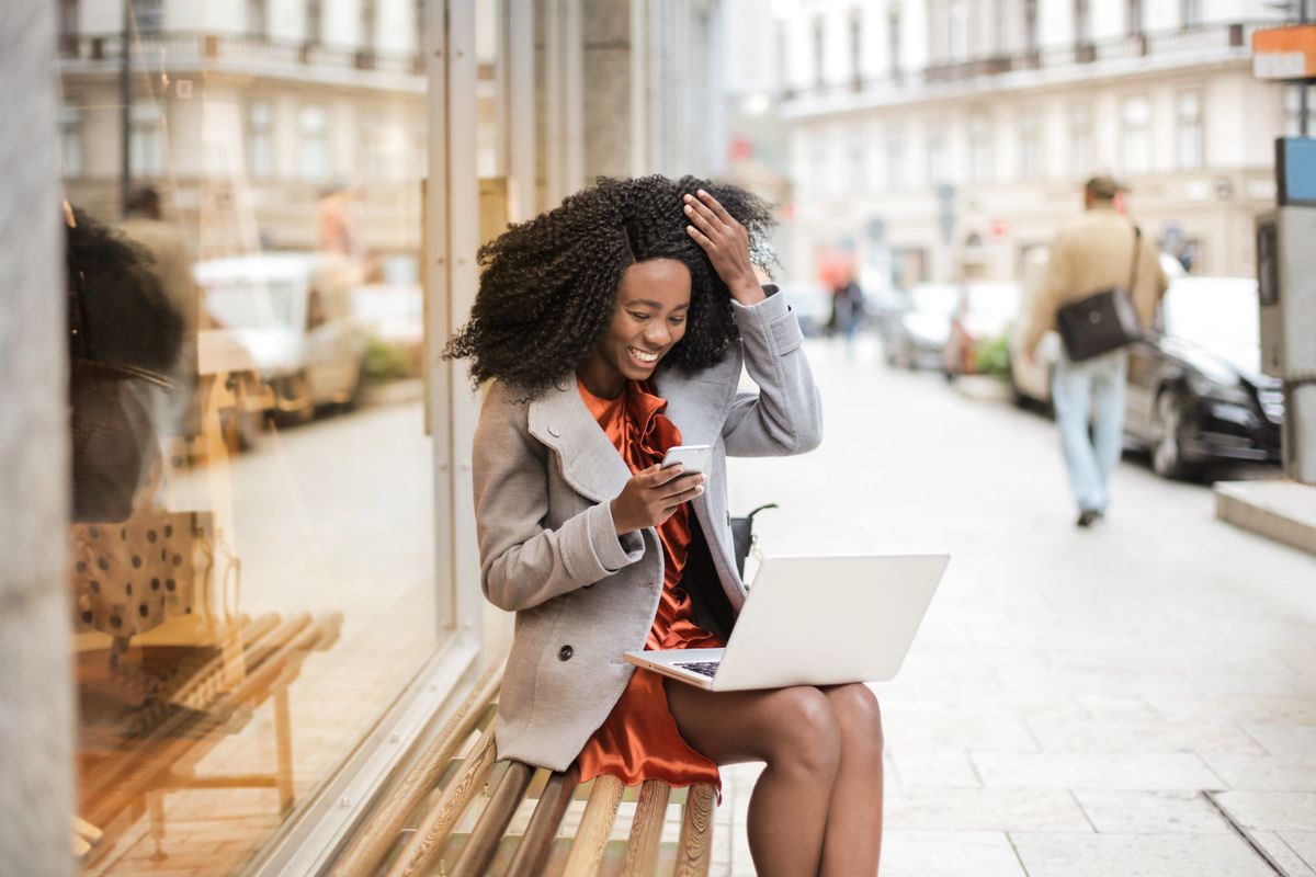 A woman laughing at her laptop in a bright, airy open-plan office