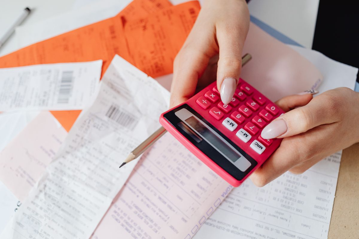 Paper receipts and a calculator spread out across a wooden desk