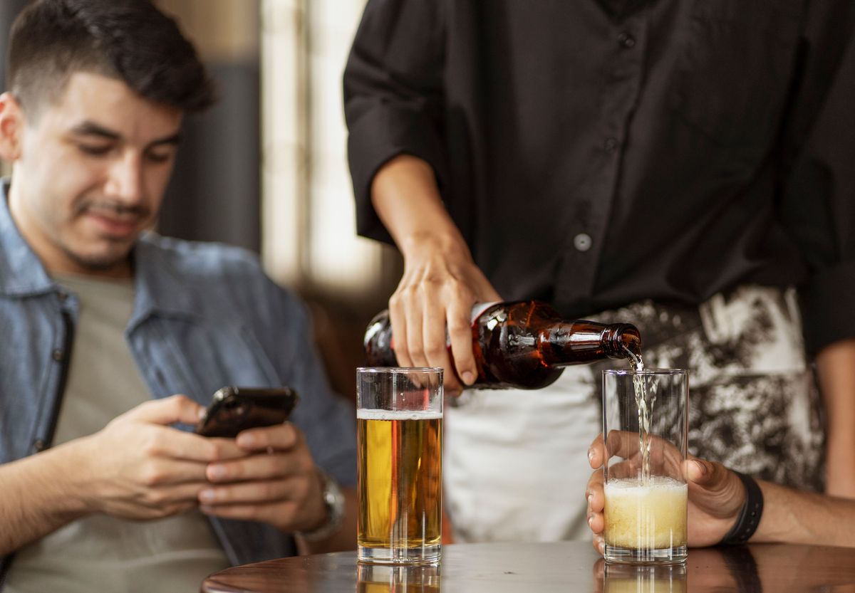 A waiter glancing at a phone in a small restaurant