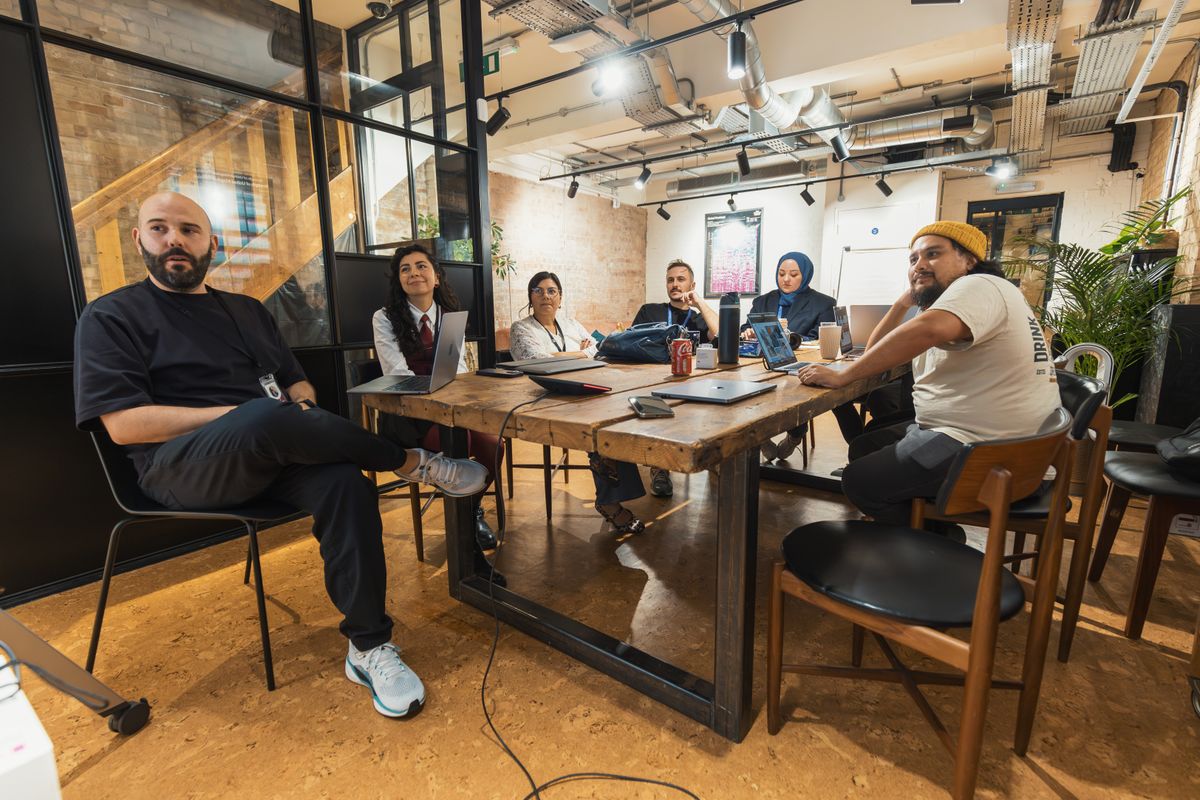 A woman speaking to colleagues seated around a meeting table