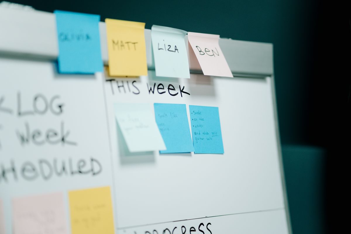 Hand placing sticky notes on a whiteboard covered in written notes