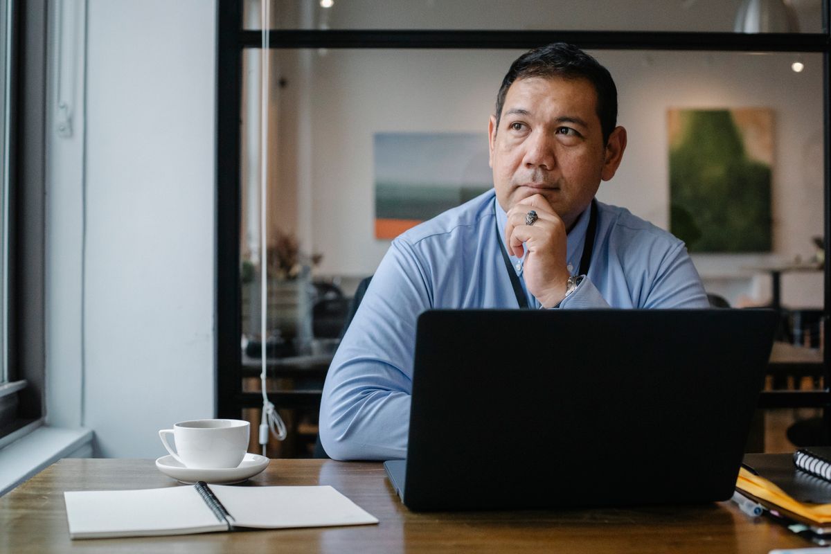 A man weighing options at a desk, laptop open in front of him