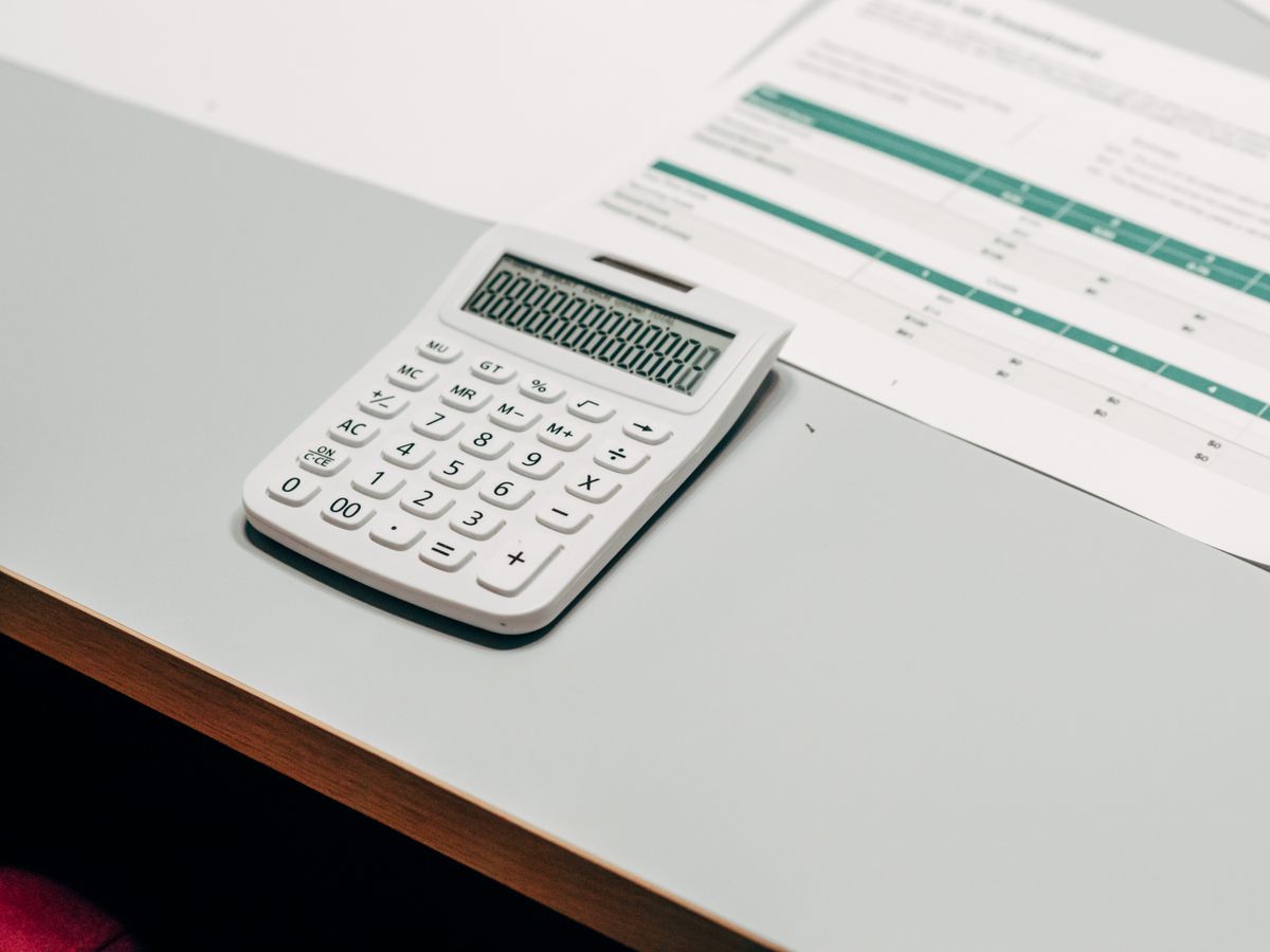 A calculator resting on a desk beside a printed spreadsheet