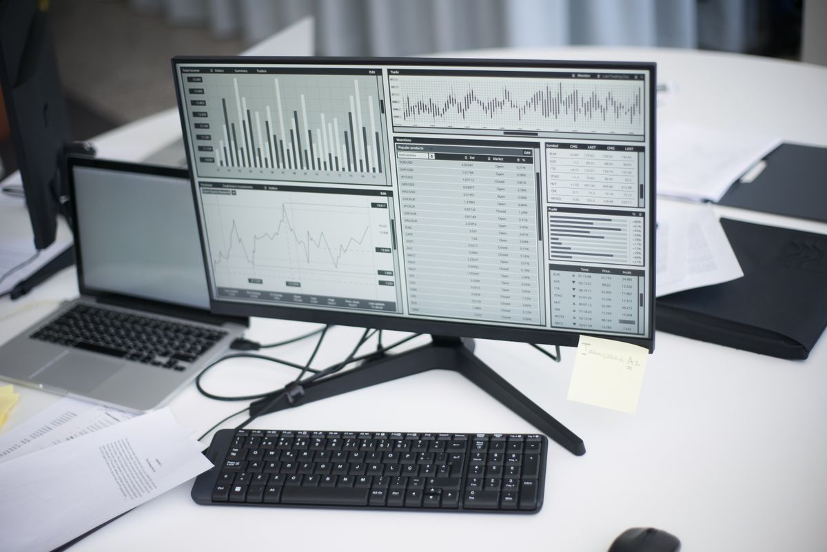 A monitor showing charts on a quiet desk in a dim office