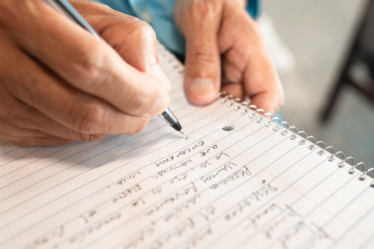 Someone writing a short numbered list in an open notebook
