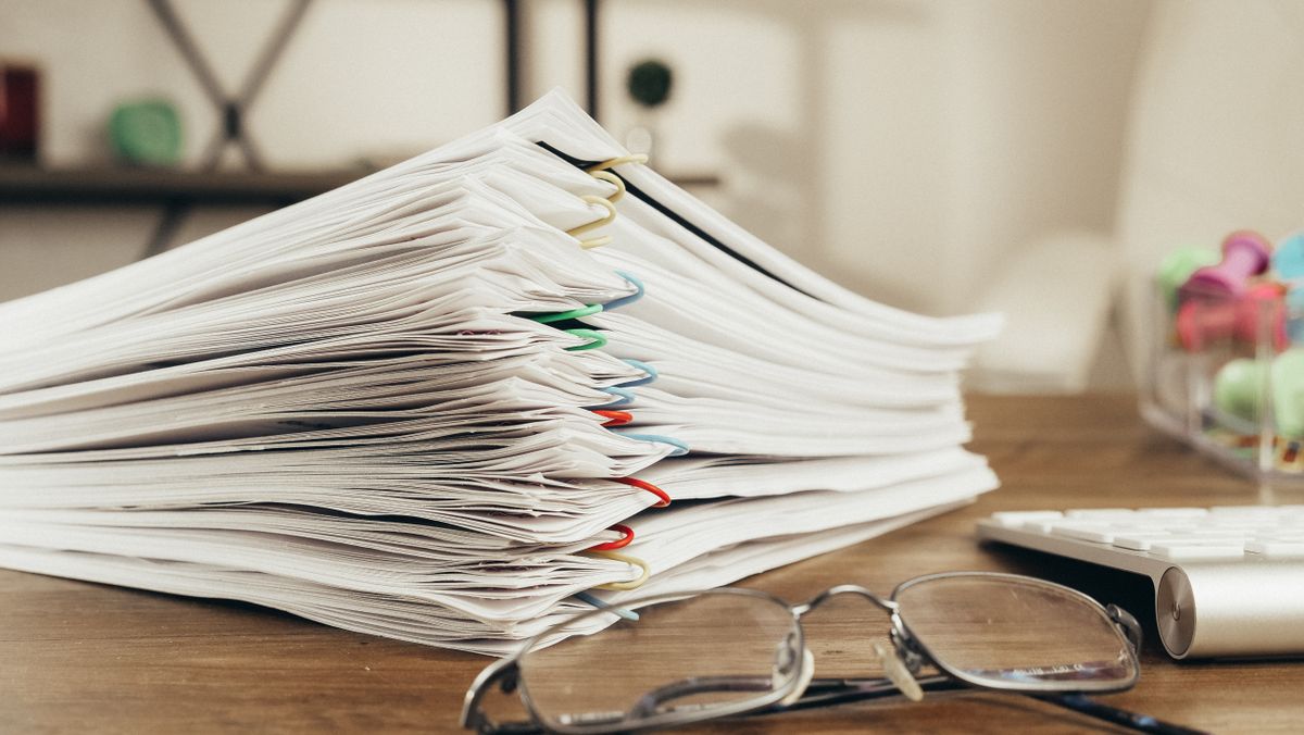 A large stack of printed documents on a desk