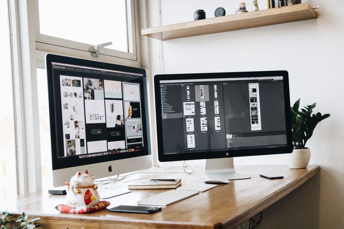 Two computer monitors sitting side by side on a wooden desk