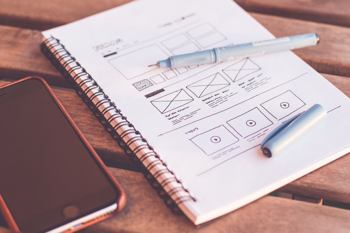 A designer sketching layout wireframes by hand in a notebook