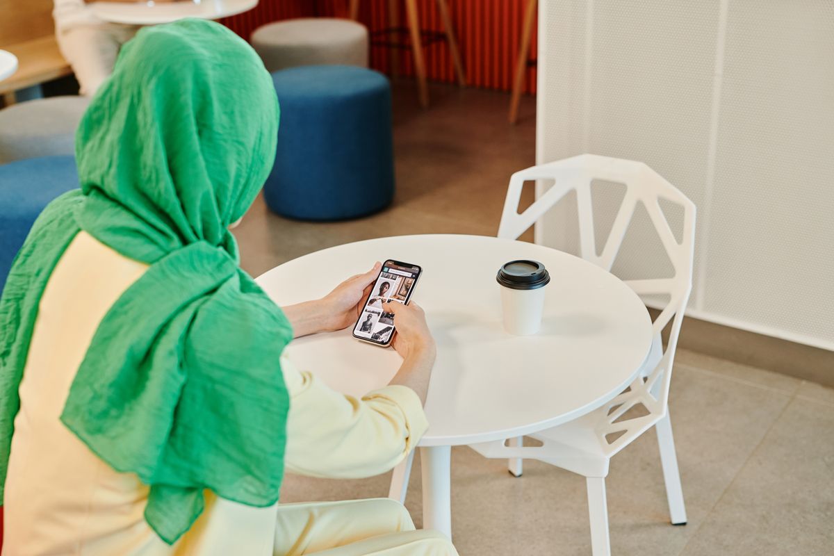 Someone scrolling through a phone at a cafe table