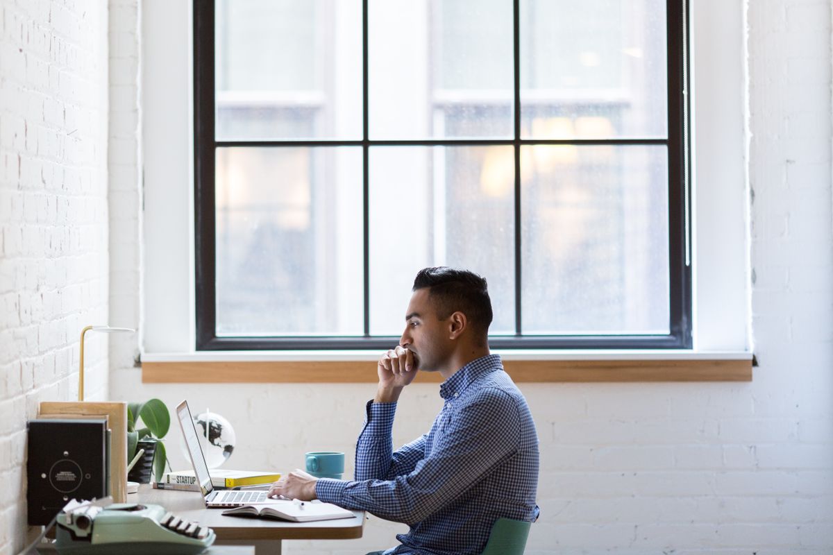 A person searching on a laptop at a desk