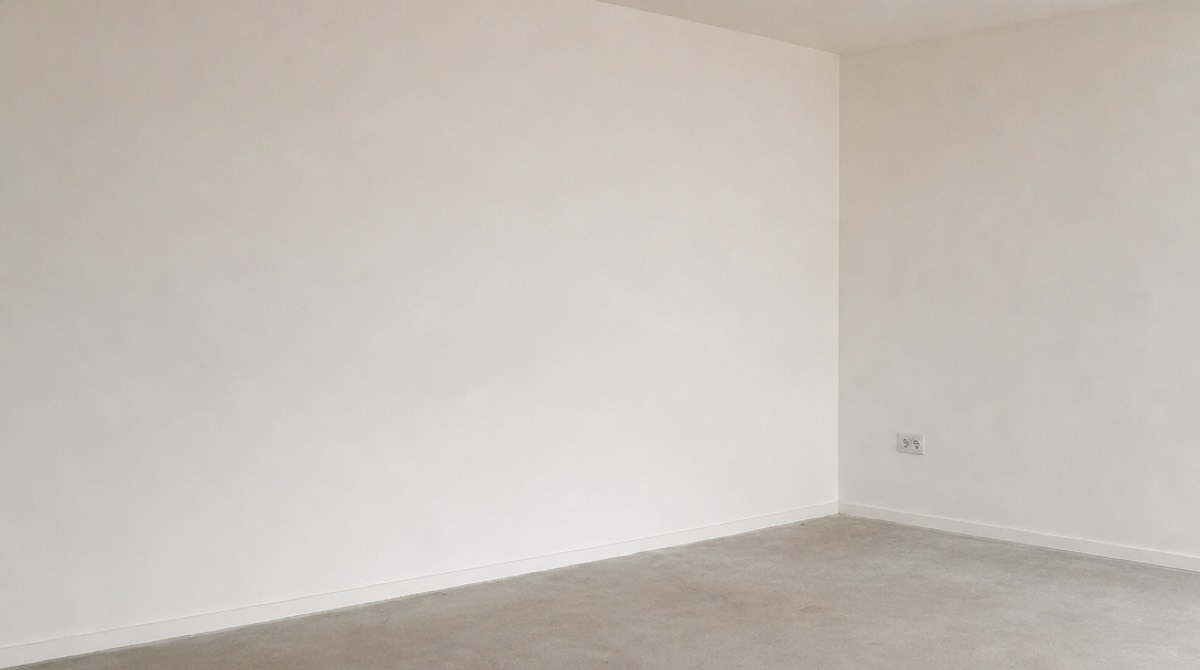 An empty studio corner with a bare wall and nothing set up